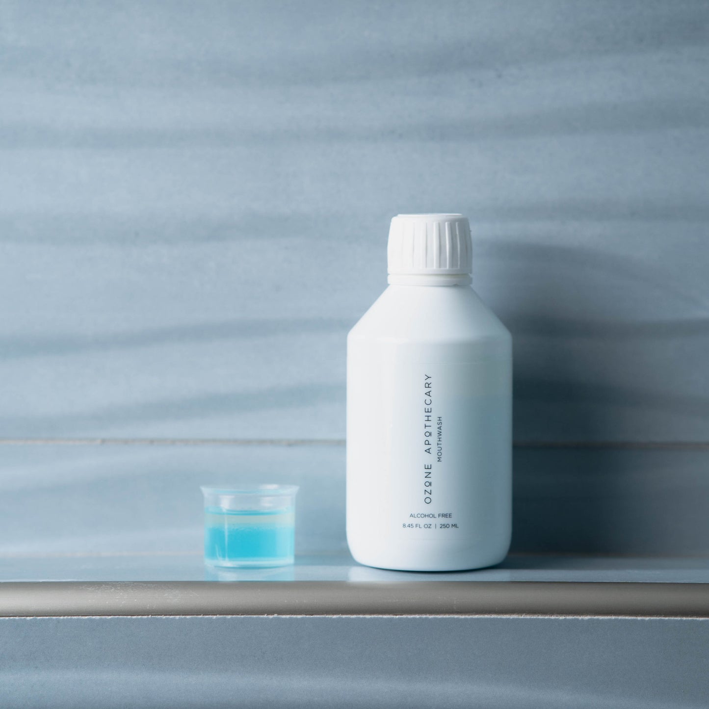 Ozone mouthwash on ledge with small cup