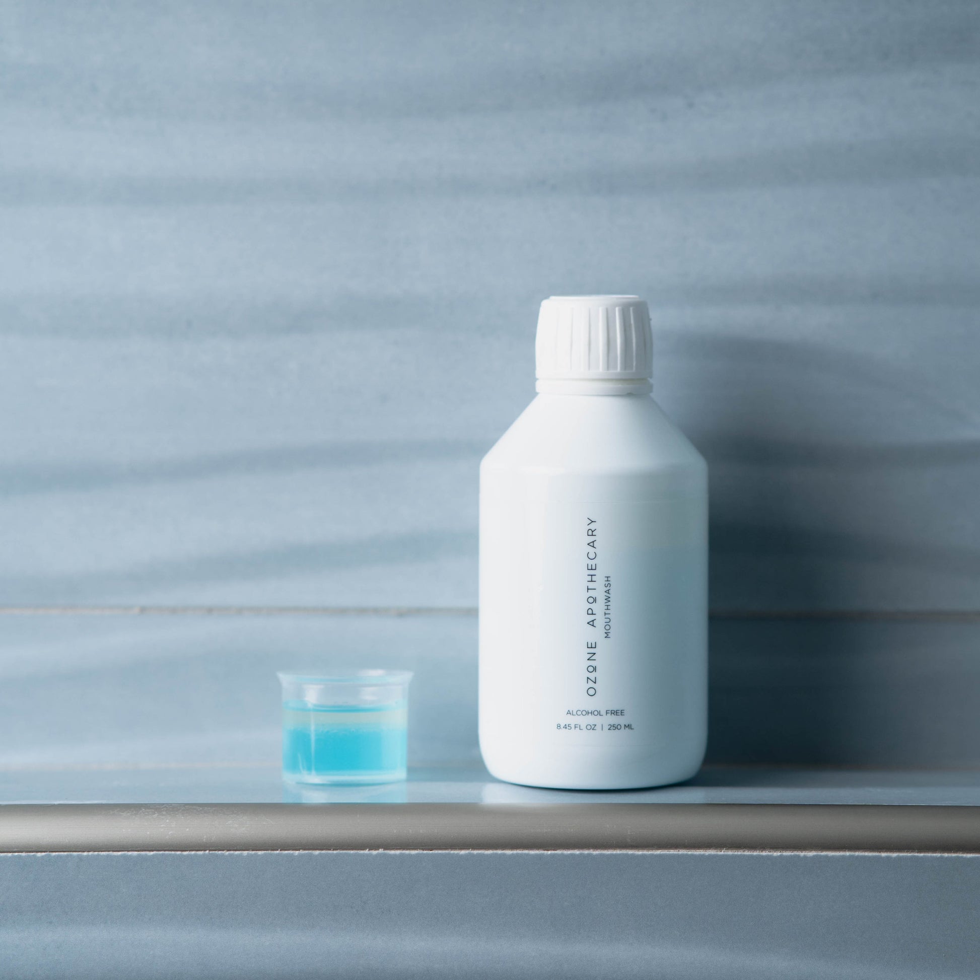 Ozone mouthwash on ledge with small cup