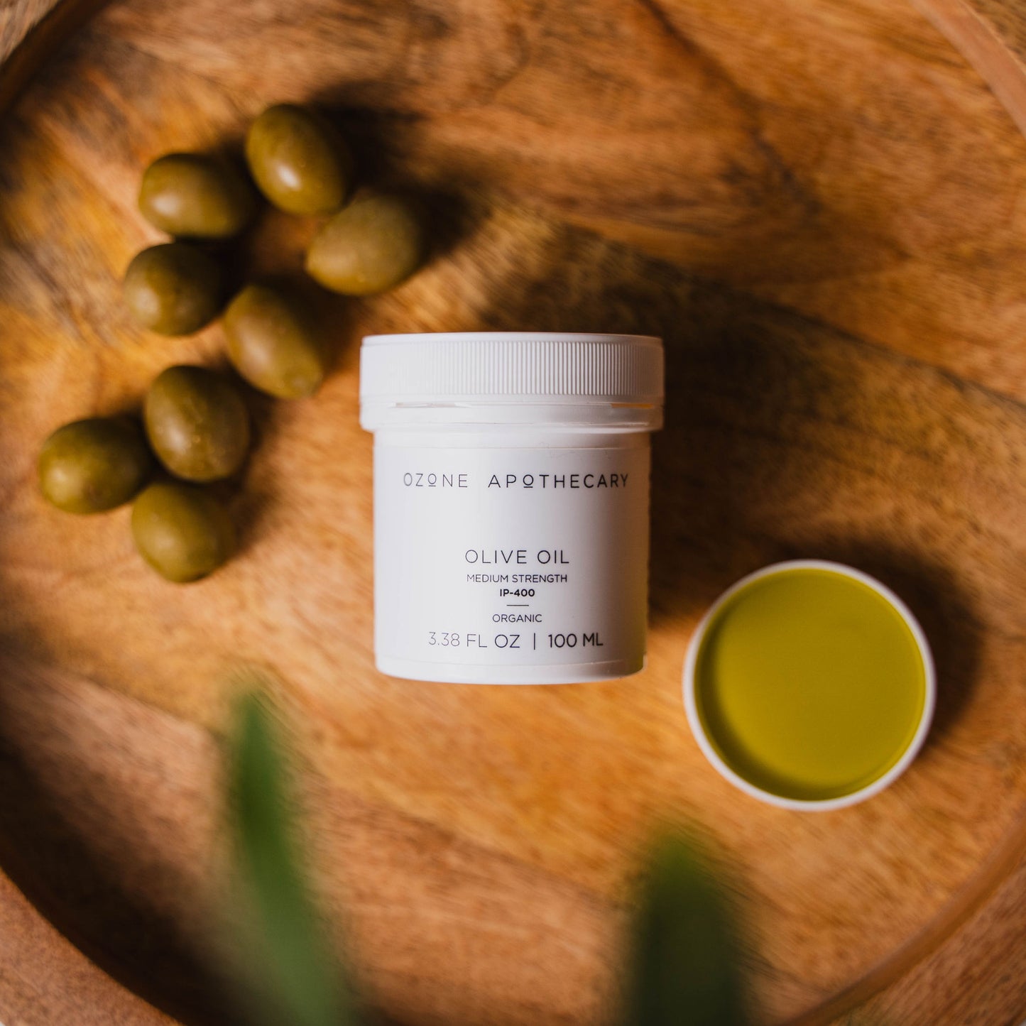 Ozone olive oil on wood platter with olives