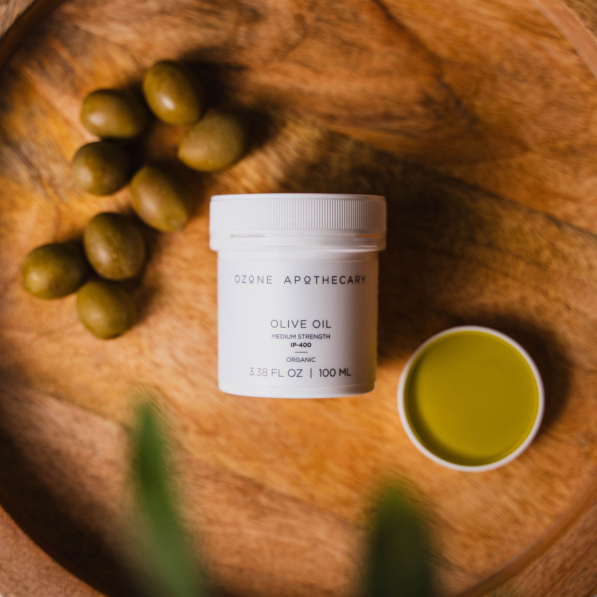 Ozone olive oil on wood platter with olives
