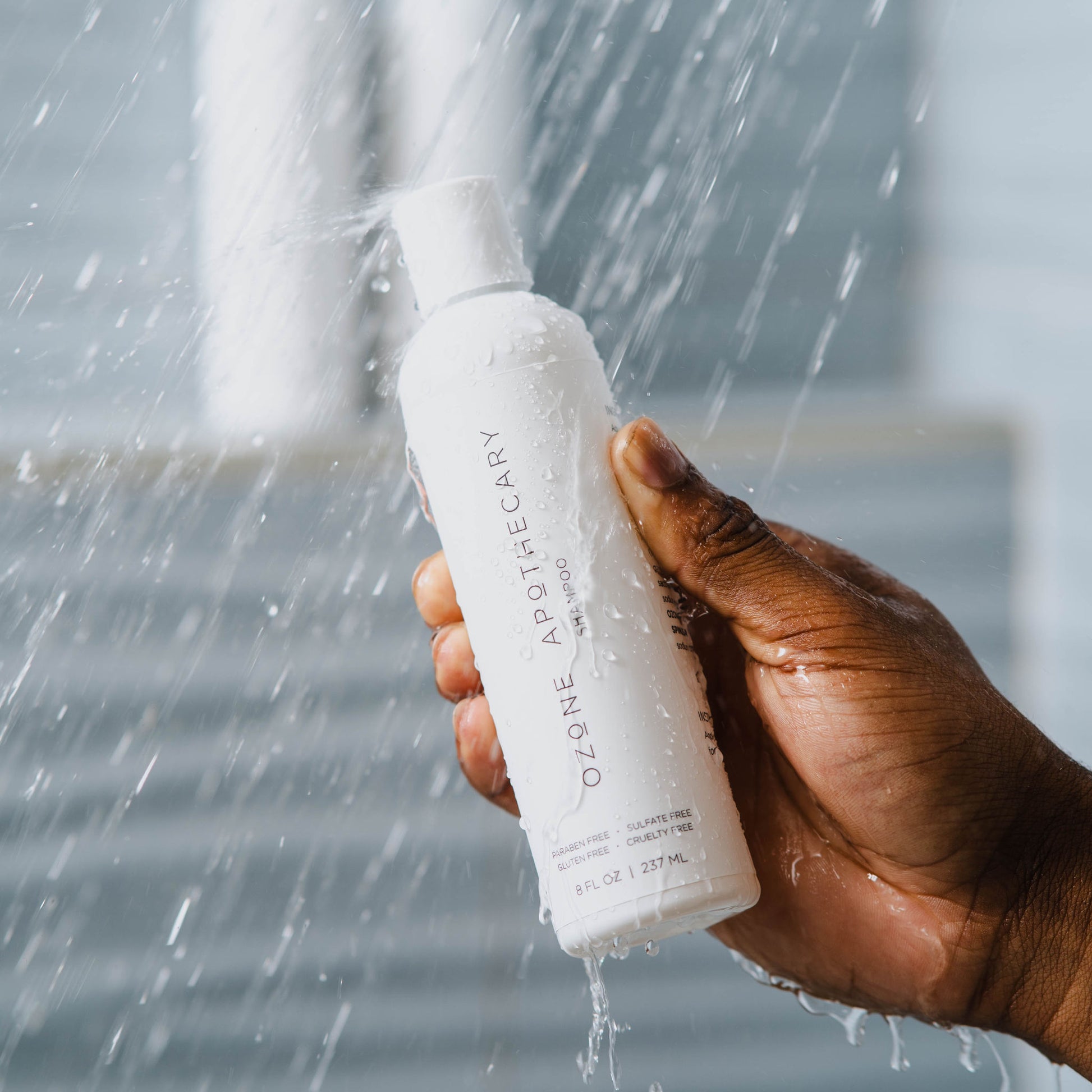 male hand holding ozone shampoo bottle in shower