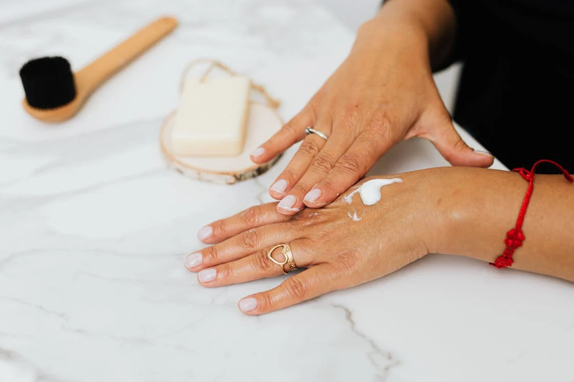 woman rubbing white cream on her hand