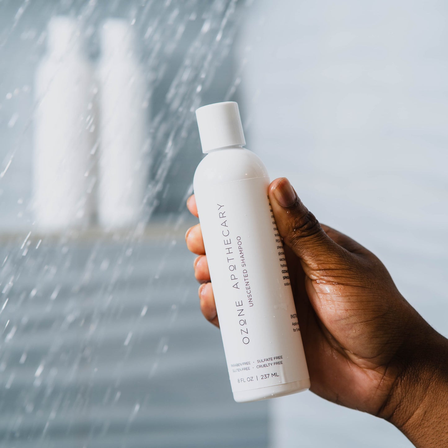Man hand showing Ozone Unscented Shampoo bottle while taking shower